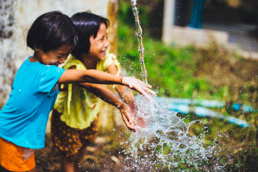 Two young girls play with a stream of water