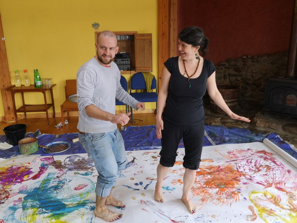 Two adults create an artwork using their painted feet